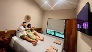 Un dormitorio con una cama, un televisor y un armario de madera.