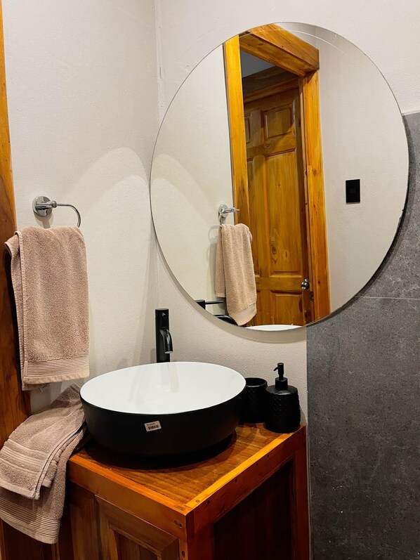 A bathroom with a round mirror, a sink, and two towels hanging on towel racks.