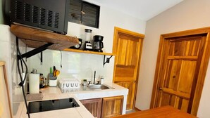 A compact kitchen with a wooden table, a built-in stove, and a coffee maker. - Jacaranda (Puerto Viejo de Talamanca)