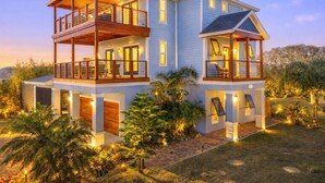 Uma casa de dois andares com varanda no andar superior, garagem e área de jardim bem iluminada.