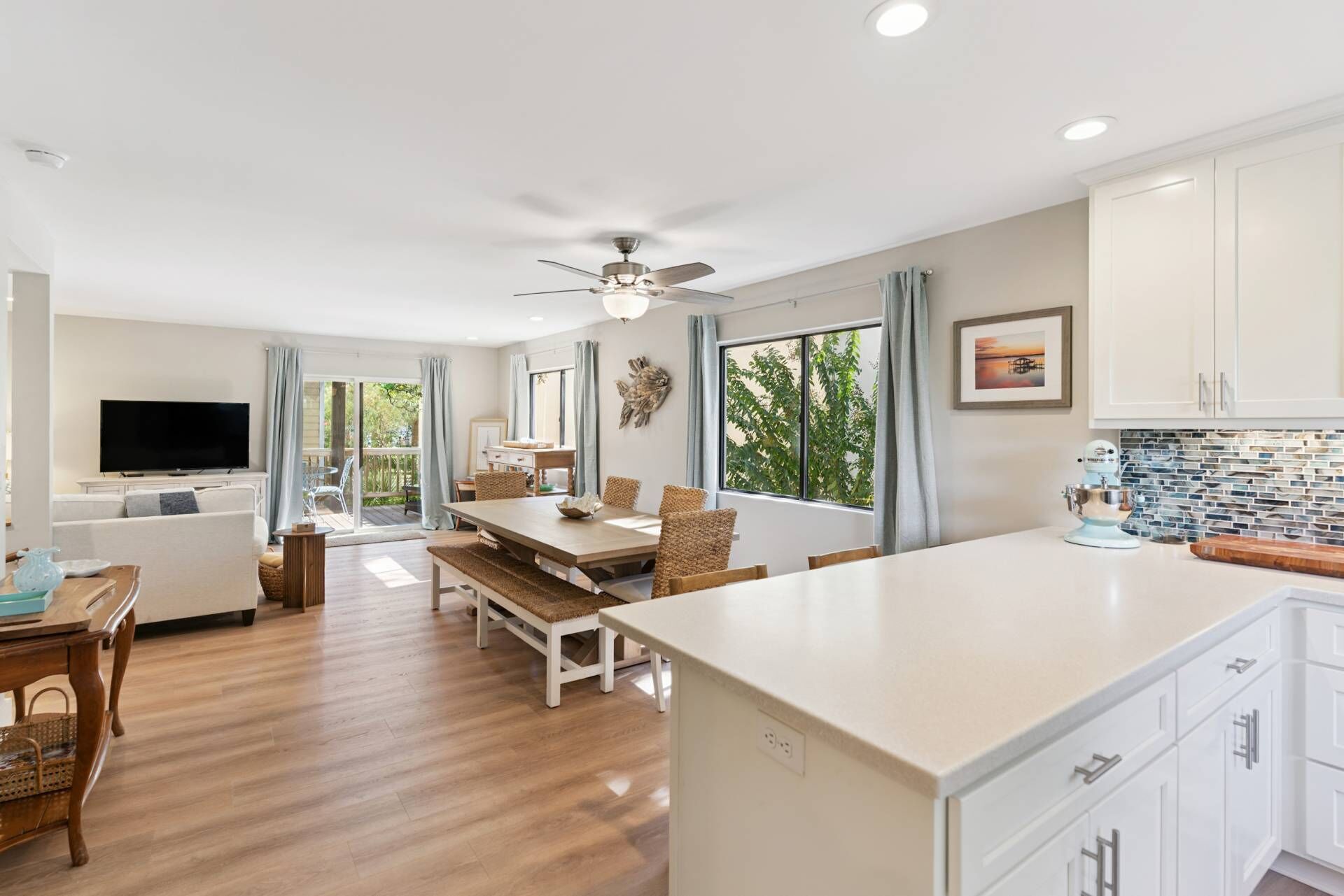 A modern kitchen with a large island, dining area, and a television in a living room.