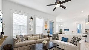 Ein modernes Wohnzimmer mit einem beigefarbenen Sofa, einem Holztisch und einem Deckenventilator.