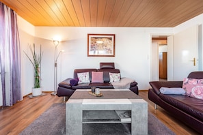 Un salon avec un canapé, une table basse, un lampadaire et un tableau accroché au mur.