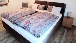 Un dormitorio con una cama grande, una mesita de noche, una silla y un cuadro en la pared.