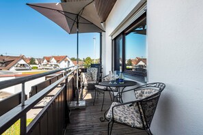 Un balcon avec une table, des chaises et une bouteille de champagne.