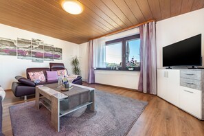 Ein modernes Wohnzimmer mit einer Couch, einem Couchtisch und einem Fernseher.