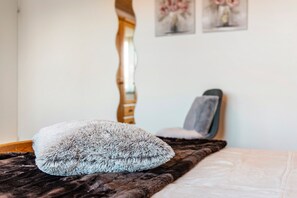 Ein Bett mit einem flauschigen Kopfkissen und einer dunkelbraunen Decke.