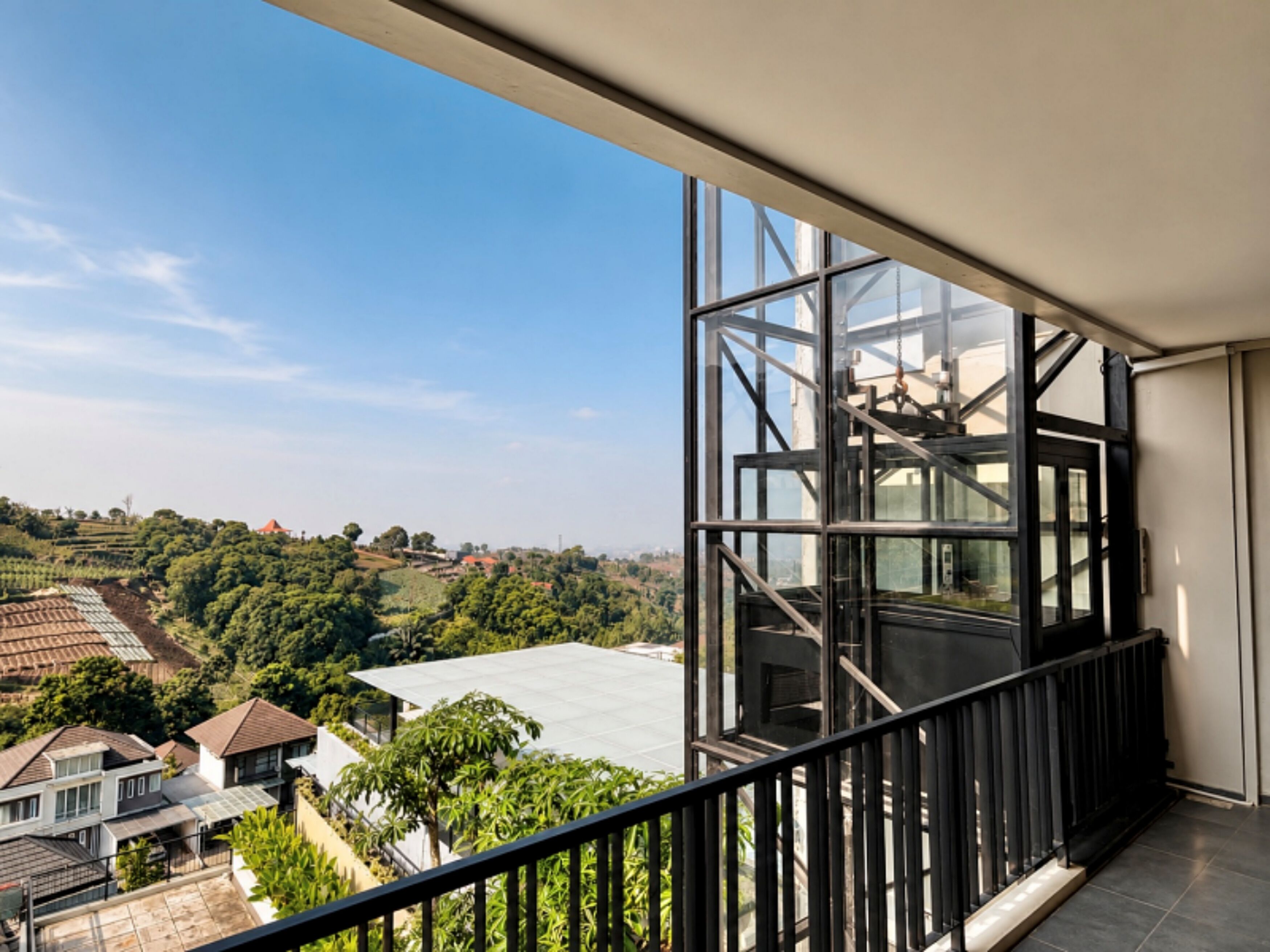 Un balcón con vistas a una zona residencial y una gran estructura de ventanales.