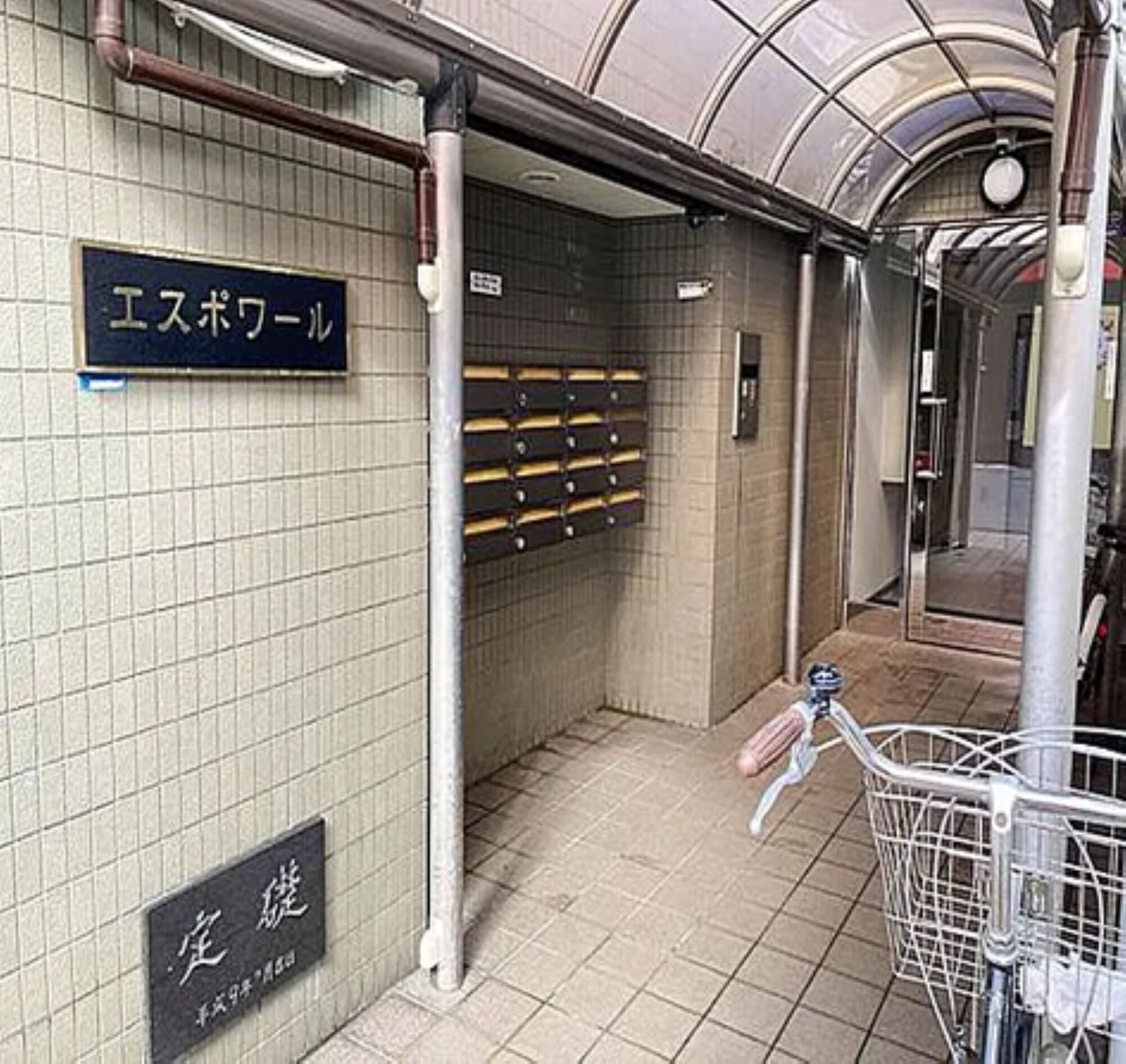 Une station de métro avec des murs recouverts de carreaux, un panneau indiquant la sortie, et un vélo garé près de l’entrée.