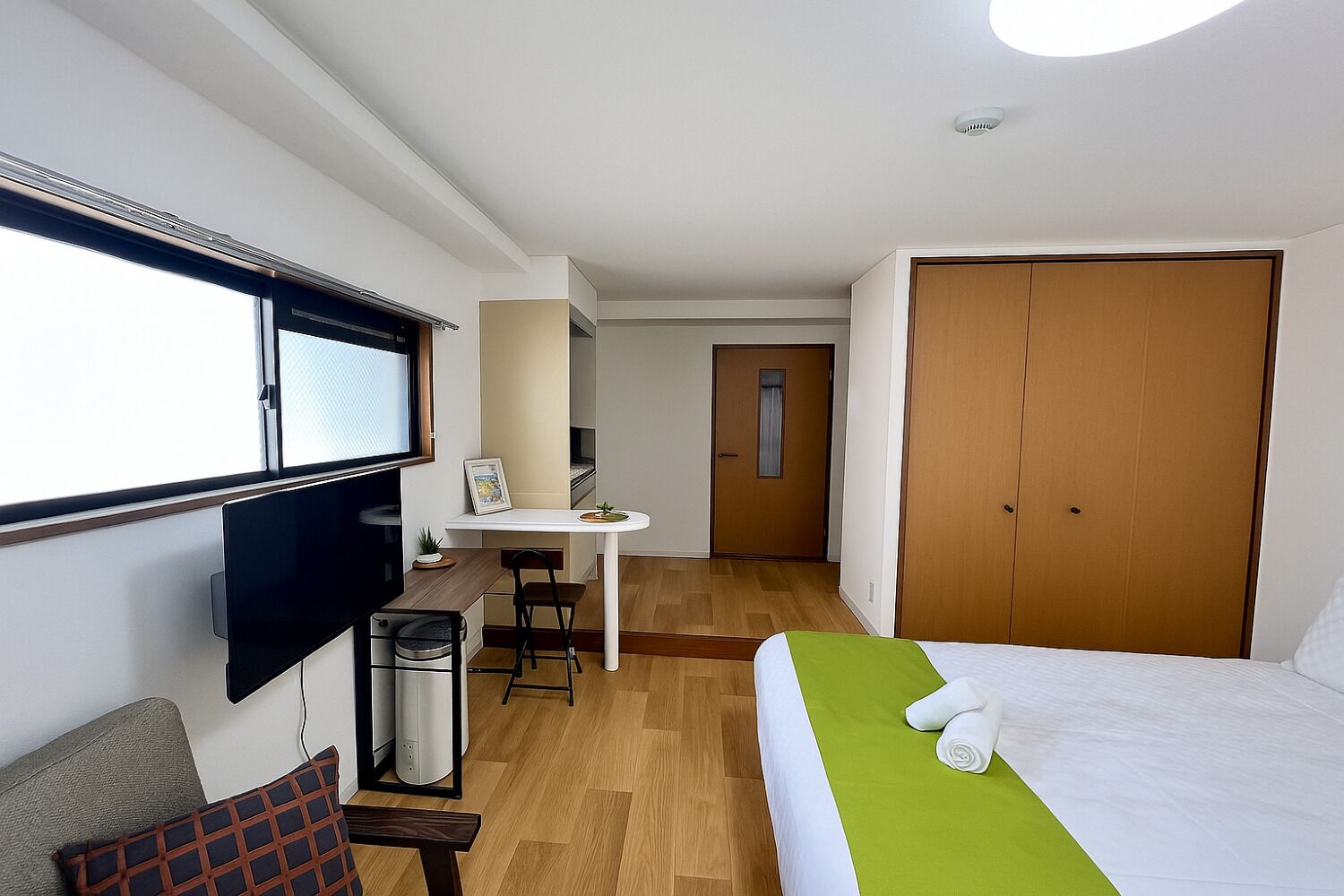 A hotel room with a bed, a desk, a TV, and a wardrobe.