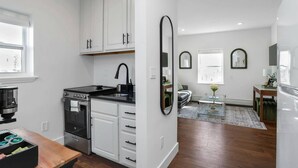 Una cocina moderna con armarios blancos, una estufa negra y un espejo grande.