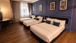 Hotellihuone, jossa on kaksi sänkyä, työpöytä ja tuoli.