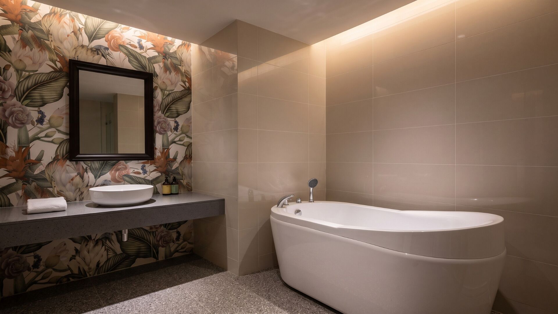 A bathroom with a freestanding bathtub, a sink with a mirror, and floral wallpaper.