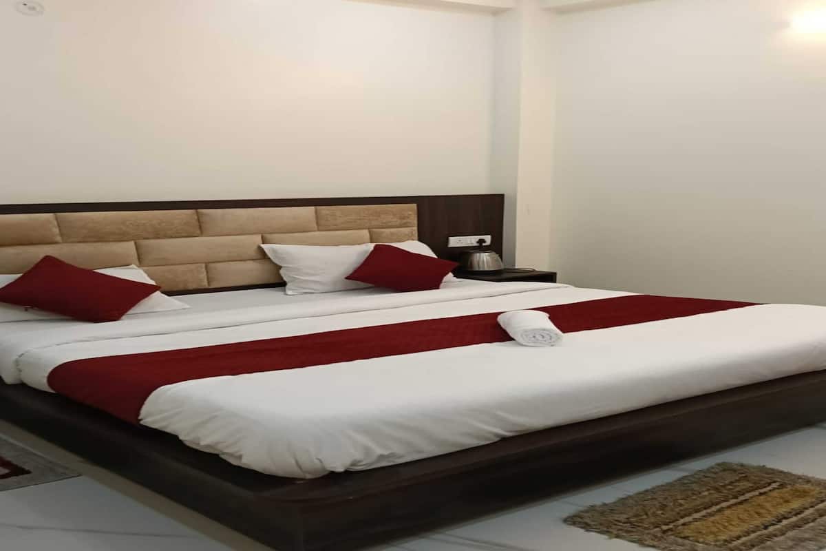 A neatly made bed with white and red bedding, a wooden headboard, and a small bedside table with a lamp.