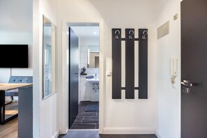 A hallway leading to a bathroom with a flat-screen TV mounted on the wall, a dark door, and a tiled floor. - Apartment 'Skipper Am Steinhuder Meer' with Wi-Fi and Air Conditioning (Wunstorf)