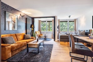 A modern living room with a sofa, coffee table, and a dining area with a table and chairs. - Apartment 'Skipper Am Steinhuder Meer' with Wi-Fi and Air Conditioning (Wunstorf)