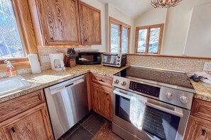 A modern kitchen with wooden cabinets, a dishwasher, a microwave, a toaster, and an oven.