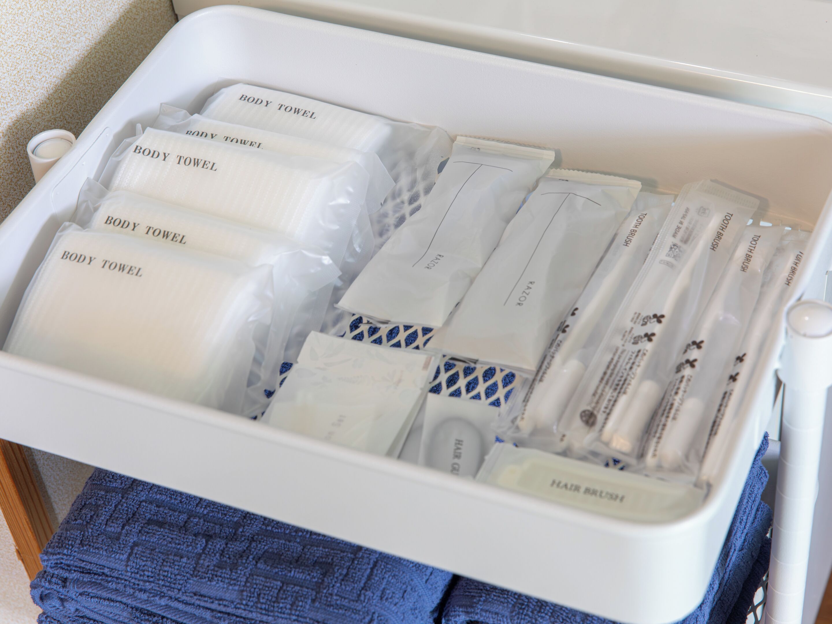 A storage bin containing multiple body towels and hairbrushes.