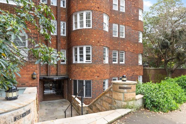 A brick building with a stone entrance, a staircase, and a sign reading "PRINCESTON".