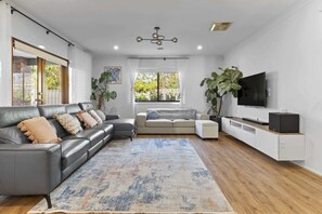 A modern living room with a grey sectional sofa, a smaller sofa, a coffee table, a TV, and a large plant.