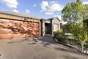 A residential property with a garage, a paved driveway, and a well-maintained garden.