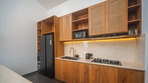 A modern kitchen with wooden cabinets, a built-in microwave, a gas stove, and a refrigerator. - Brand New 3Bedroom Lucky Lotus Villa Private Pool (Bali)