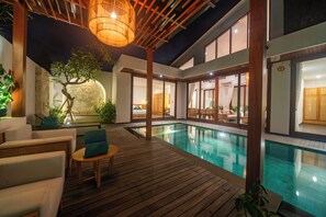 Ein Poolbereich mit Holzterrasse, Liegestühlen und einem Tisch.