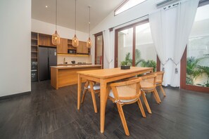 Una cocina moderna con armarios de madera, refrigerador empotrado e iluminación colgante.