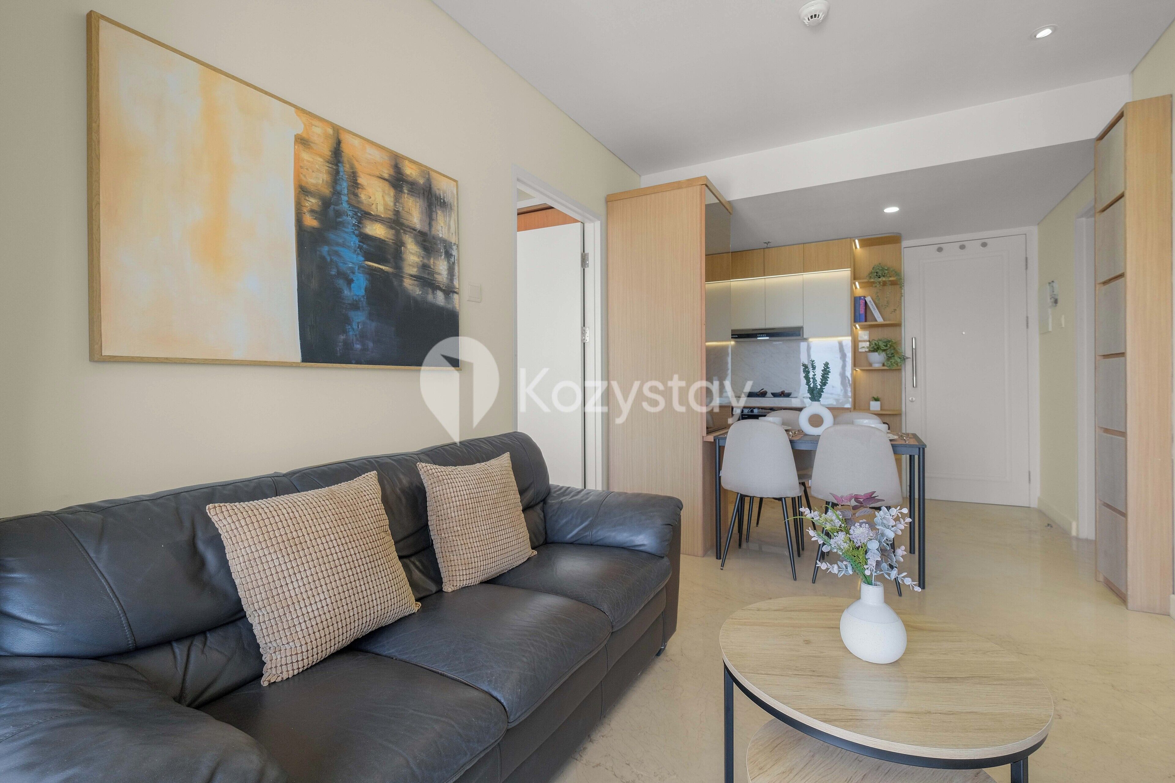A modern living room with a leather sofa, a coffee table, and a painting on the wall.