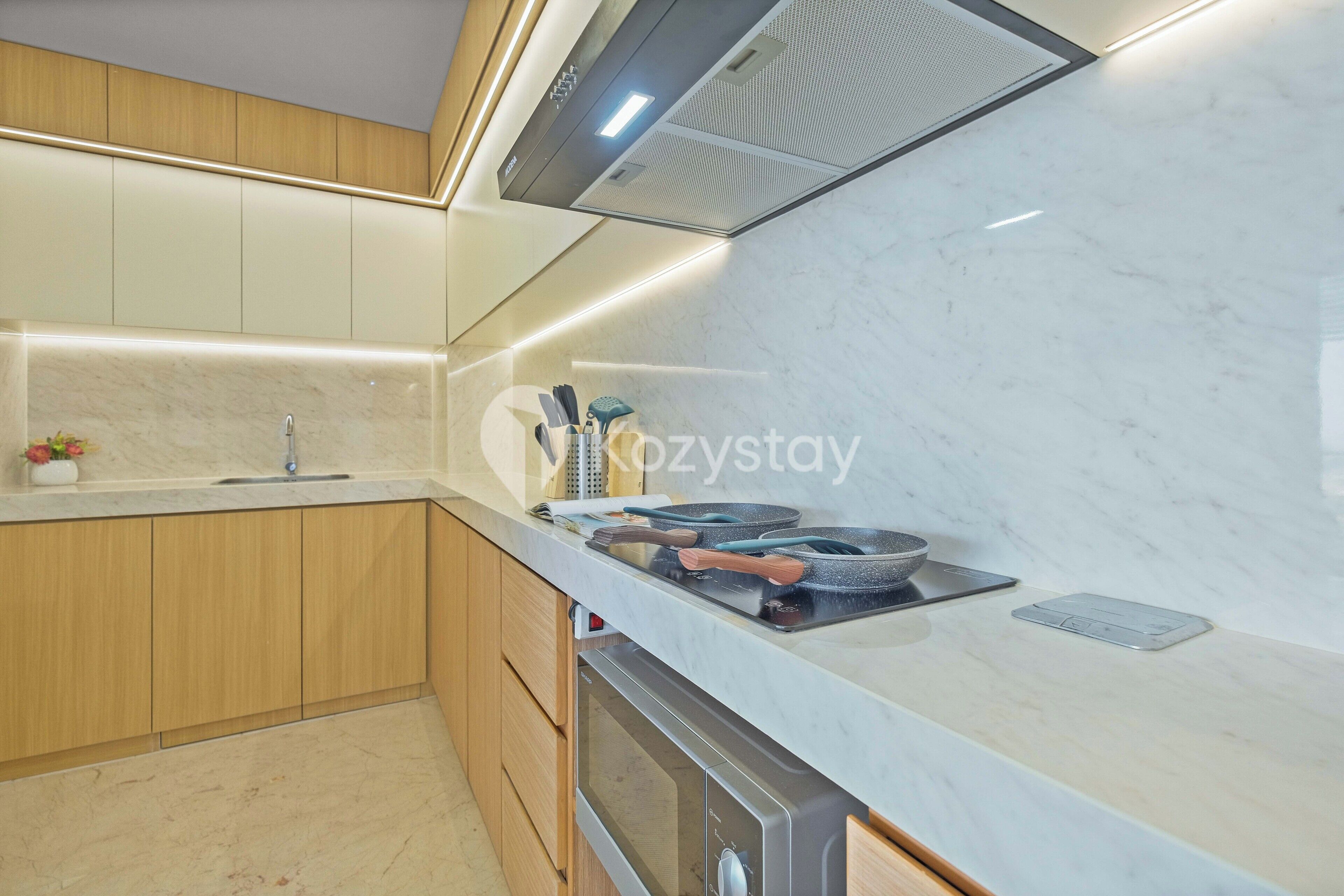 Una cocina moderna con armarios de madera, horno empotrado y campana extractora de acero inoxidable.