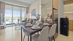 A modern dining area with a large table set for four, a sofa, and a view of the city. - Tirava by Kozystay - Paskal (Bandung)