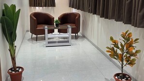 Una sala de estar moderna con dos sofás de cuero marrón, una mesa de centro blanca y dos plantas en macetas.