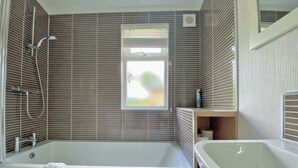 Un baño moderno con bañera, ducha y ventana.