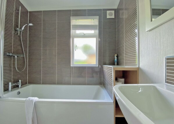 Un baño moderno con bañera, ducha y ventana.