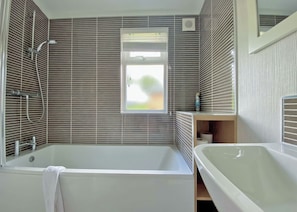 Un baño moderno con bañera, ducha y ventana.