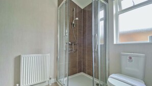 A bathroom with a glass-enclosed shower, a white toilet, a radiator, and a window. - 1 bedroom accommodation in Tunstall, Richmond (Tunstall, Richmond)