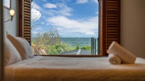 A bedroom with a large window overlooking a coastal view.
