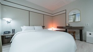 Een moderne hotelkamer met een groot bed, nachtkastje, lamp en een spiegel.