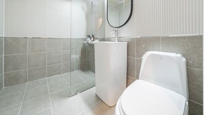 Een moderne badkamer met een douche, wastafel en toilet.