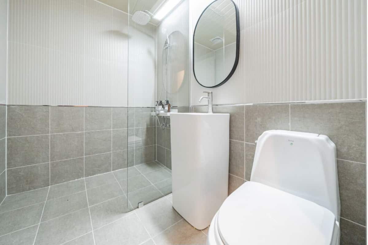 A modern bathroom with a shower, sink, and toilet.
