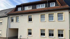 Um edifício de dois andares com telhado plano e várias janelas.