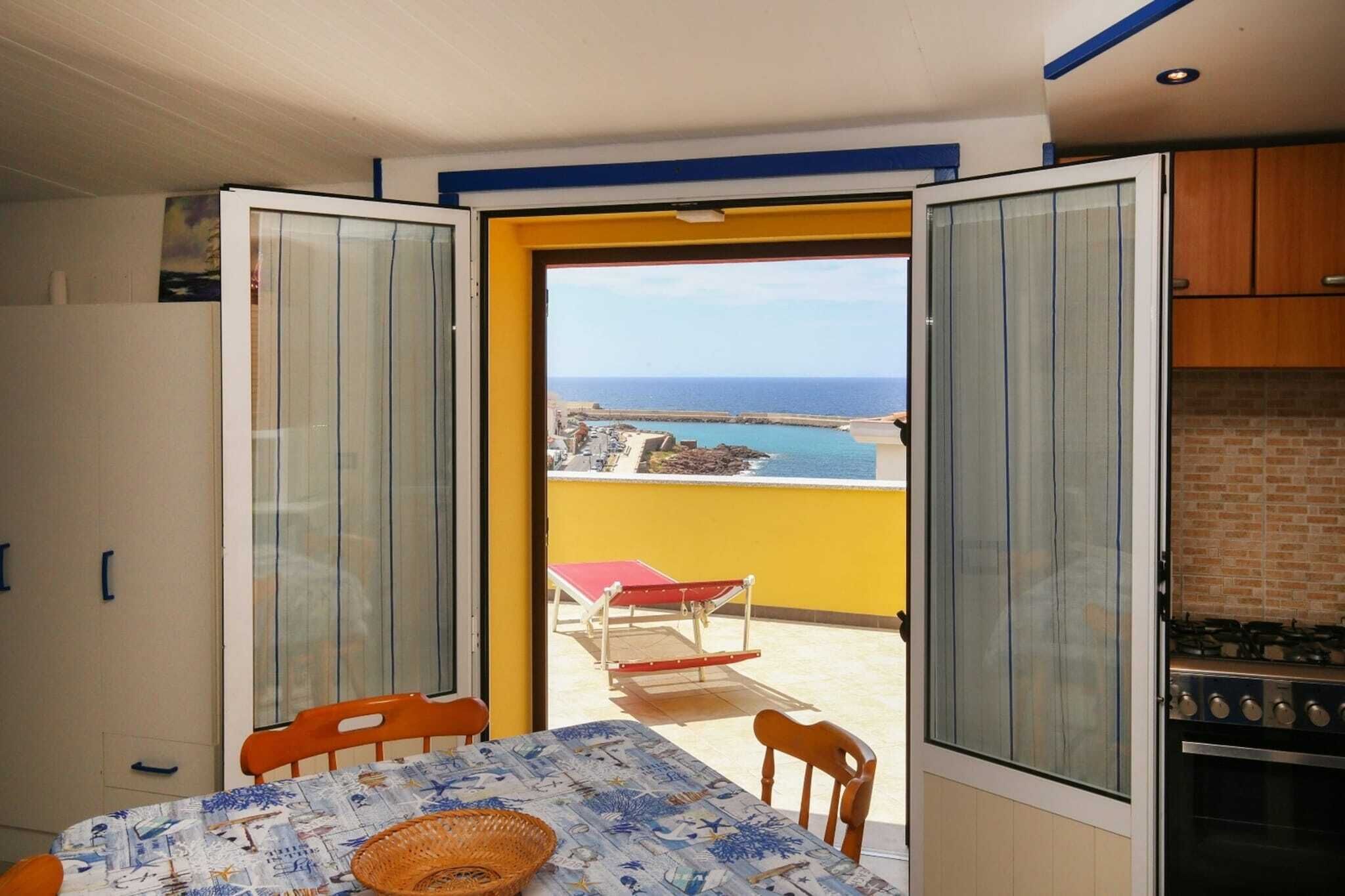 Een balkon met een tafel en stoelen, een uitzicht op zee en een kitchenette.