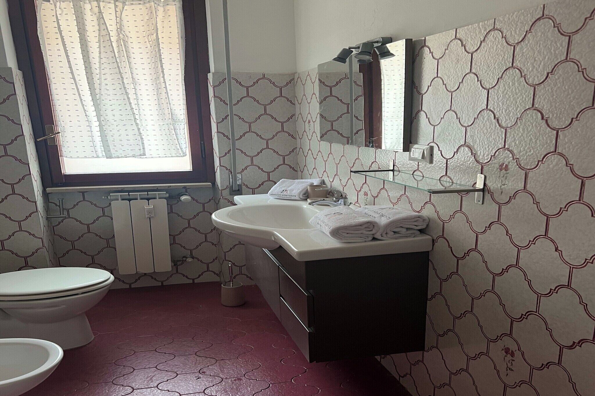 Un bagno con un water, un lavandino e uno specchio.
