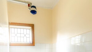 Casa de banho pequena e limpa, com sanita, janela e zona de chuveiro.