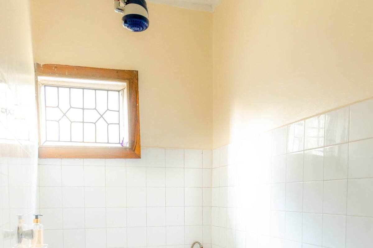 A small, clean bathroom with a toilet, a window, and a shower area.