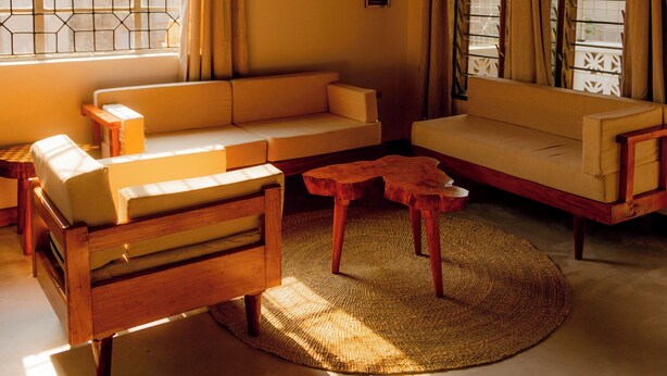 Uma sala de estar acolhedora com teto de madeira, um sofá, um banco de madeira e uma mesa de centro.