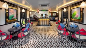 Eine Hotelhalle mit einem gemusterten Boden, roten und blauen Sesseln und Kunstwerken an den Wänden.