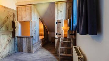 Una habitación rústica con paredes de madera, una cama en altillo, una escalera y un radiador.