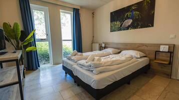 Una camera da letto con un letto, una scrivania, una sedia, una finestra con tende e un quadro appeso al muro.