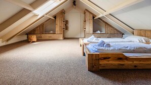 Ein Schlafzimmer im Loftsstil mit schrägem Dach, Holzmöbeln und Teppichboden.